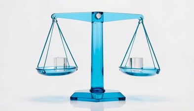 A blue glass balance scale with its two pans hanging level, a small clear glass cube in each pan